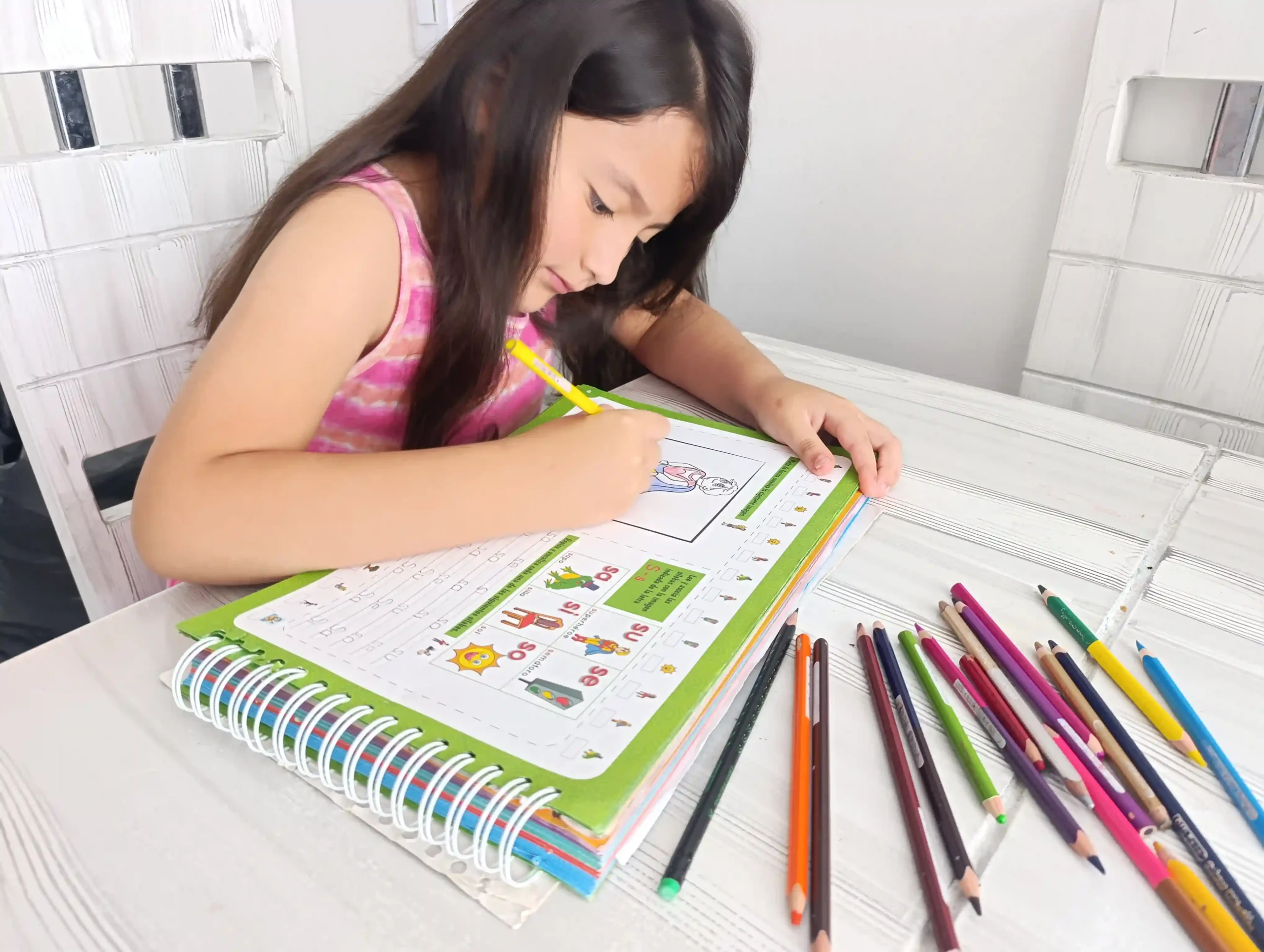 Niña practicando lectura y escritura con el libro El Tesoro de Esteban y sus Amigos